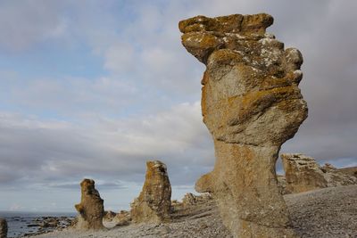 Rock formations at beach against sky