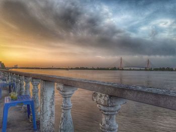 Bridge over sea against cloudy sky
