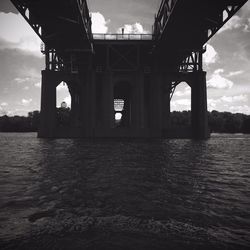 Bridge over river against cloudy sky