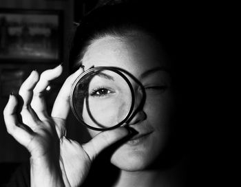 Portrait of woman looking through bangle in darkroom