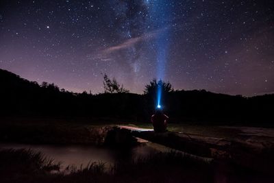 Man on illuminated mountain against sky at night