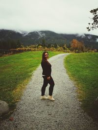 Full length portrait of woman standing on landscape against sky