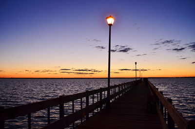 Pier over sea against sky during sunset