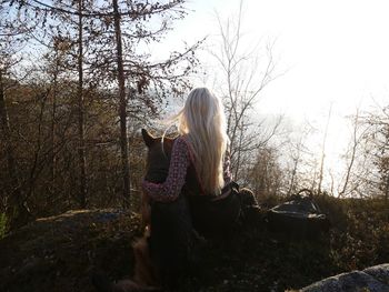 Rear view of woman and dog sitting in forest