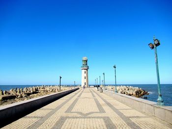 Street by sea against clear blue sky