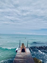 Rear view of man on pier over sea against sky