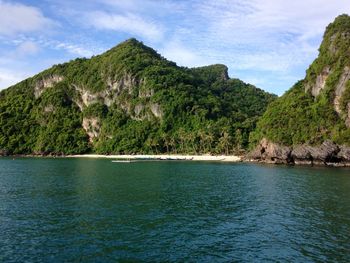 Scenic view of sea by mountains against sky