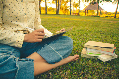 Midsection of man reading book on field