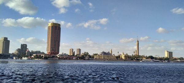 Sea by buildings against sky in city