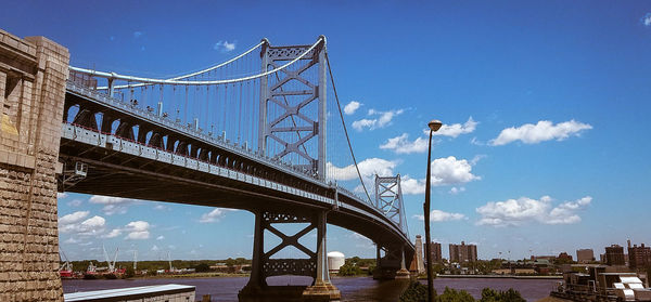 Low angle view of suspension bridge against blue sky