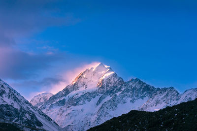 Scenic view of snowcapped mountains against blue sky