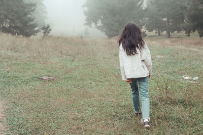 Rear view of woman walking on field