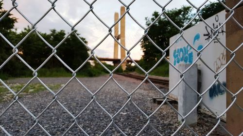 Bridge against sky seen through chainlink fence