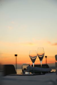 Wineglasses on table against sky during sunset