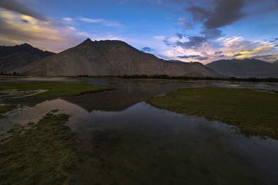 Scenic view of lake by mountains against sky