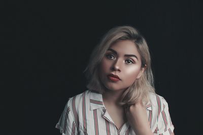 Portrait of a beautiful young woman over black background