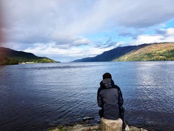 Rear view of man looking at sea against sky