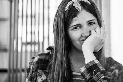 Portrait of smiling young woman with hand on chin sitting indoors