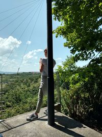 Man standing by tree against sky