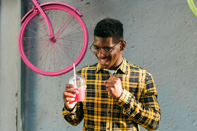 Young man using mobile phone against wall