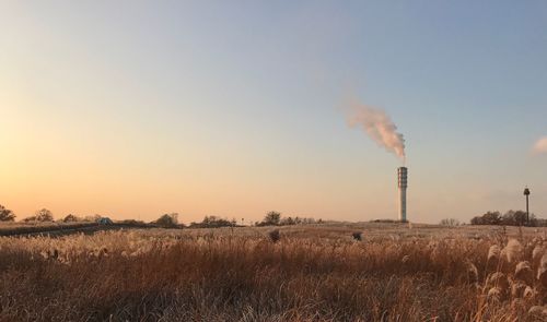 Smoke emitting from chimney on field against sky