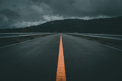 Empty road by mountains against sky at night