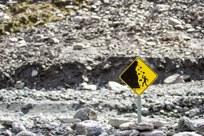 Close-up of road sign on rocks at beach
