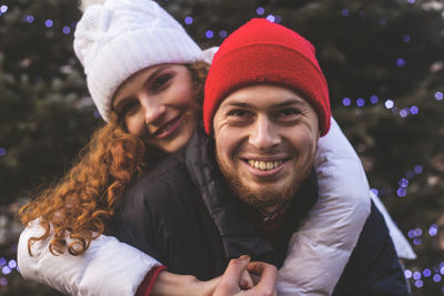 Loving boyfriend and girlfriend are hugging happily near a big city christmas tree