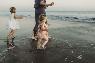 Behind view of young family walking towards the ocean at sunset