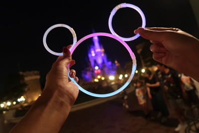 Close-up of hand holding illuminated lighting equipment at night