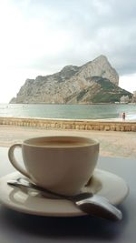 Close-up of coffee on table by sea against sky