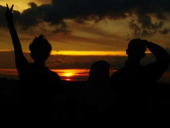 Silhouette people sitting against sky during sunset