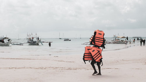 Taken at boracay, philippines. a man carrying lifevest for their guests