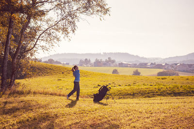 Side view of woman playing golf on grassy land