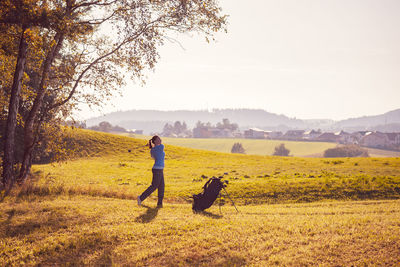 Full length of young woman with horse on field