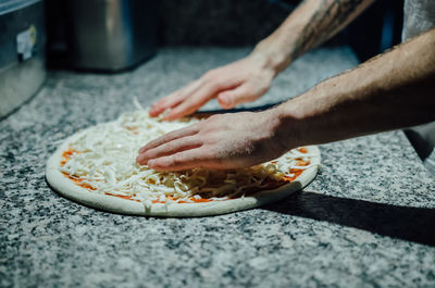 Cropped image of chef preparing pizza at kitchen counter