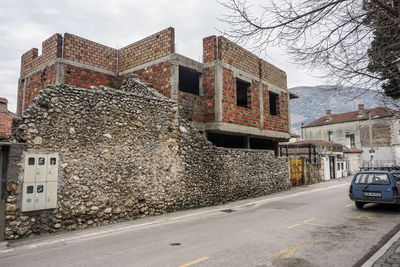 Road by buildings in city against sky