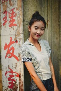 Portrait of young woman standing against wall