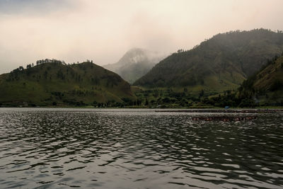 Scenic view of lake by mountains against sky