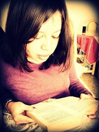 Close-up of girl sitting on book at home