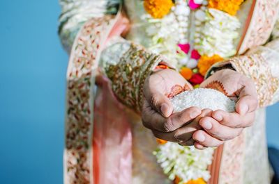 Midsection of groom standing with rice in hands