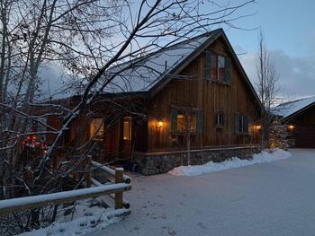 Snow covered house by building against sky