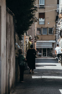 Rear view of people walking on street amidst buildings