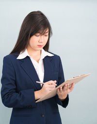 Young woman using smart phone against white background