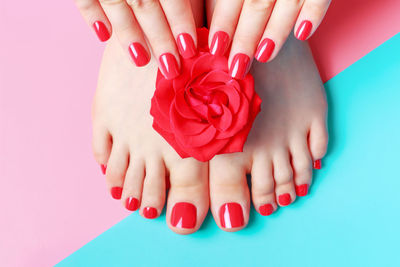 Female hands with manicure and feet with pedicure on a blue and pink background.