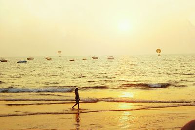 Silhouette person on beach against sky during sunset