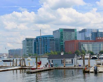 Modern buildings by river against sky in city