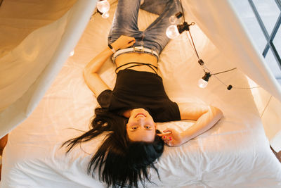 Young woman is lying in a four-poster bed with glowing light bulbs
