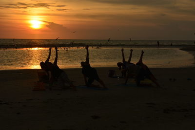 Yogis on beach during sunset