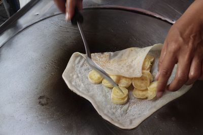 Close-up of person preparing banana crepe